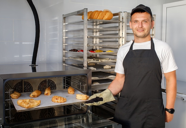 Un giovane fornaio in una panetteria tiene in mano dei pasticcini