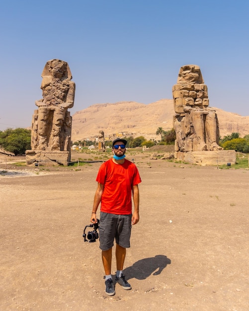 Un giovane fotografo in visita a due sculture egizie nella città di Luxor lungo il Nilo in Egitto