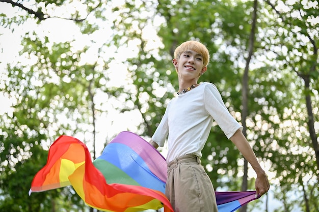 Un giovane gay asiatico spensierato con una bandiera arcobaleno LGBTQ LGBTQ Pride month