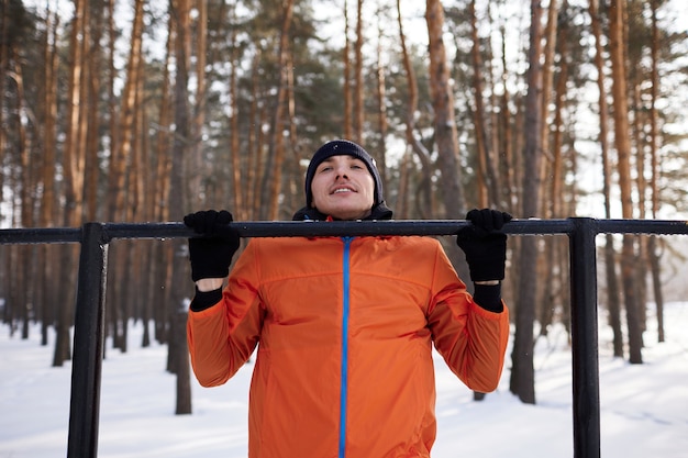 Un giovane in abiti sportivi luminosi è impegnato in un allenamento su un campo sportivo in una giornata invernale