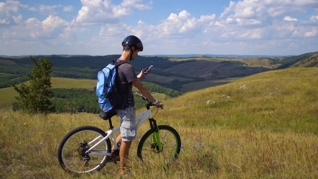 Un giovane in bicicletta è guidato dal terreno usando una mappa sul suo cellulare