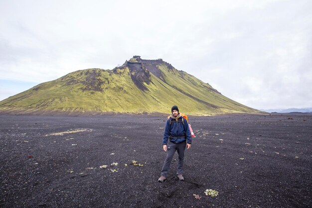 Un giovane in cenere vulcanica e una montagna verde a Landmannalaugar in Islanda