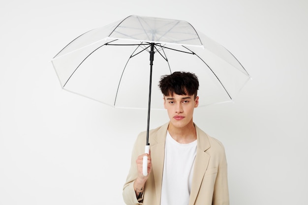 Un giovane in possesso di un ombrello nelle mani di posa di moda sfondo chiaro inalterato