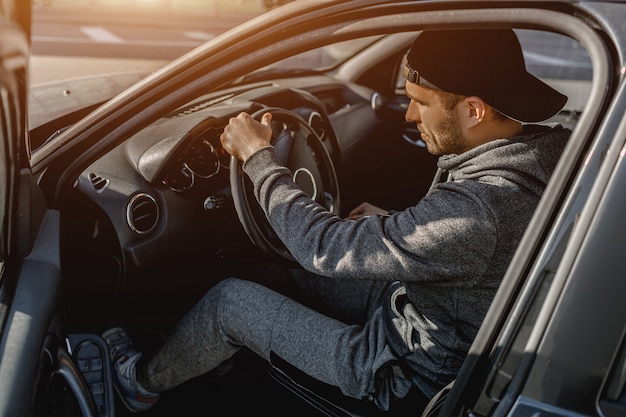 Un giovane in tuta è seduto nella sua auto.