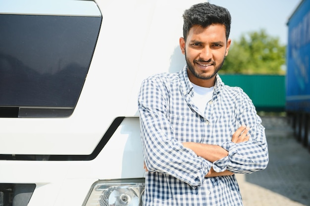 Un giovane indiano in piedi davanti al suo camion.