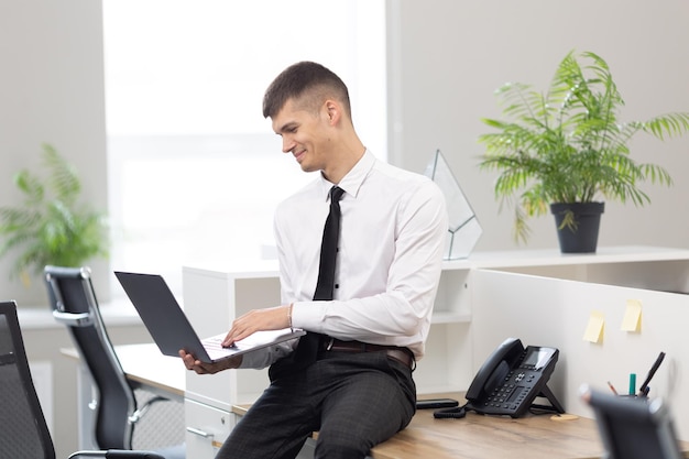 Un giovane libero professionista con una camicia bianca usa un laptop mentre è seduto in ufficio