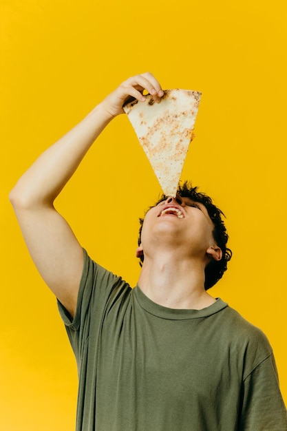 Un giovane mangia un pezzo di pizza Foto in studio su copyspace di sfondo a colori