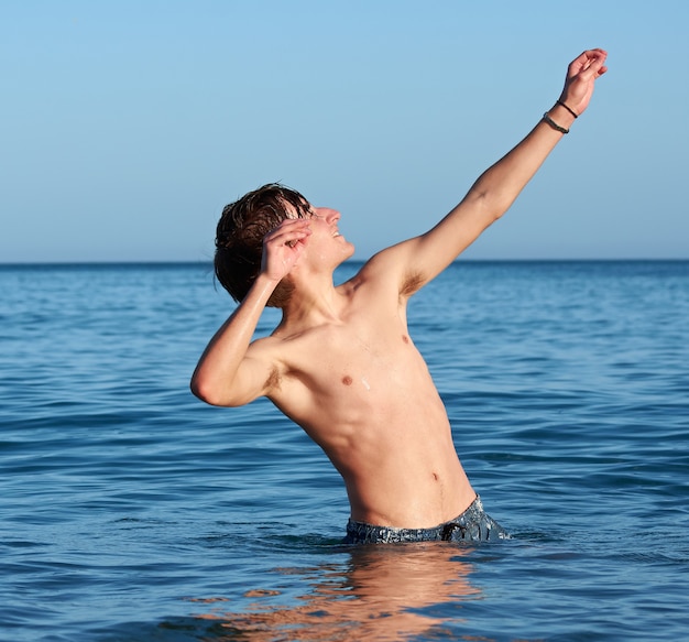 Un giovane maschio caucasico in forma in posa e si diverte in mare
