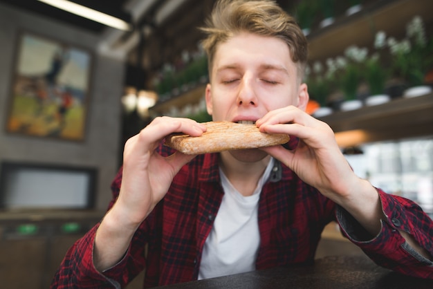 Un giovane morde un panino in un bar accogliente.