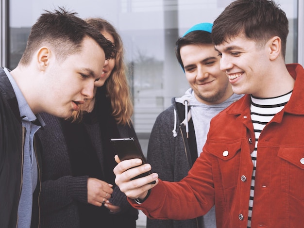 Un giovane mostra qualcosa di divertente sul suo smartphone a un gruppo di amici adolescenti