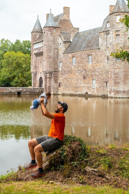 Un giovane padre con il suo bambino in visita al castello medievale in riva al lago di Trecesson, comune di CampÃƒÂƒÃ‚Â©nÃƒÂƒÃ‚Â©ac nel dipartimento del Morbihan, vicino alla foresta di Broceliande.
