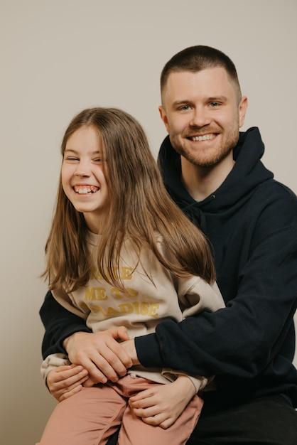 Un giovane padre sorridente con la barba abbraccia fortemente sua figlia carina.