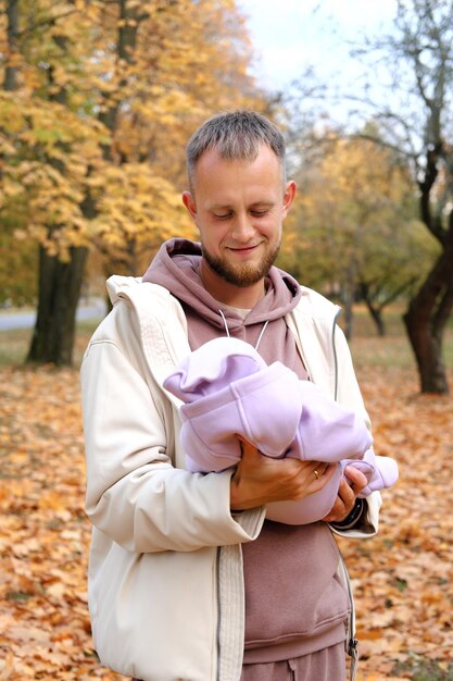 Un giovane padre tiene in braccio una figlia neonata in tuta viola