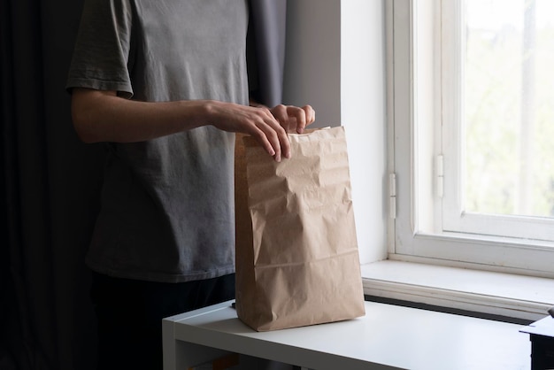 Un giovane porta il cibo a casa e apre dei sacchetti di carta sul tavolo