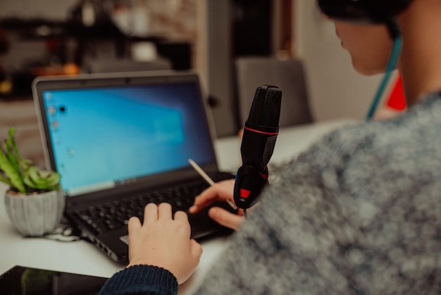 Un giovane ragazzo con cuffie moderne studia da casa usando un laptop