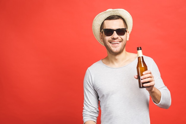 Un giovane ragazzo con un cappello e occhiali da sole tiene una bottiglia di birra