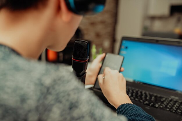 Un giovane ragazzo in cuffia moderna studia da casa usando un laptop