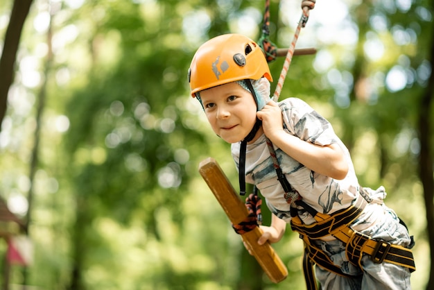 Un giovane ragazzo in una sosta in montagna e infradito attraversa un percorso a ostacoli. Attività attiva e sportiva in estate per un bambino.