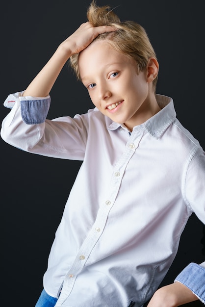 Un giovane ragazzo si aggiusta i capelli mentre posa