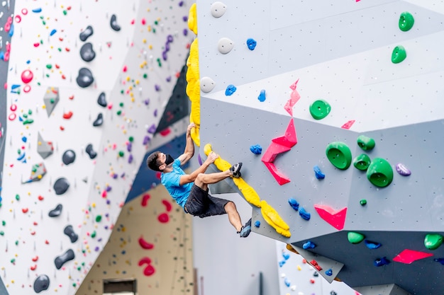 Un giovane scalatore maschio che pratica l'arrampicata su una parete da arrampicata.