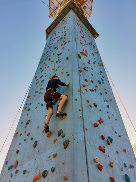 Un giovane si arrampica sul muro per arrampicarsi con attrezzature speciali Vista dal basso