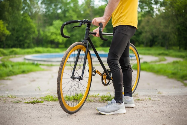 Un giovane si è fermato a riposare con la sua bicicletta in un parco pubblico. Si gode una mattina presto soleggiata nella foresta