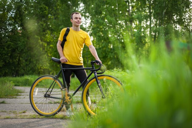 Un giovane si è fermato a riposare con la sua bicicletta in un parco pubblico. Si gode una mattina presto soleggiata nella foresta