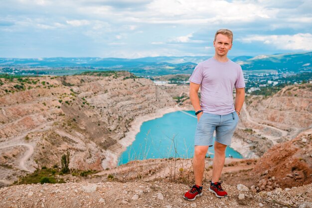 Un giovane si trova in una cava a forma di cuore con acqua turchese in Crimea