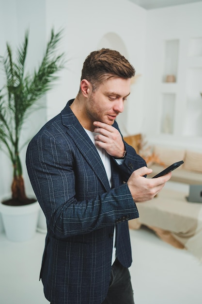 Un giovane sorridente con una giacca sta parlando al telefono Emozioni di risate dal parlare al telefono Un uomo di successo lavora a distanza al telefono