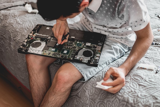 Un giovane sta cambiando la pasta termica su un laptop