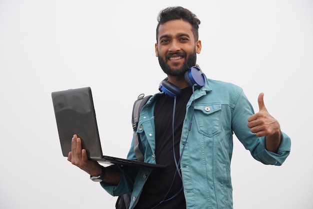 Un giovane studente che rinuncia a tumnbs con laptop e cuffie