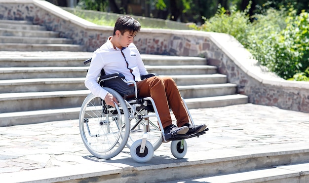 Un giovane su una sedia a rotelle che non riesce a scendere le scale.