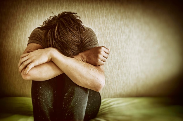 Un giovane triste seduto a letto a casa