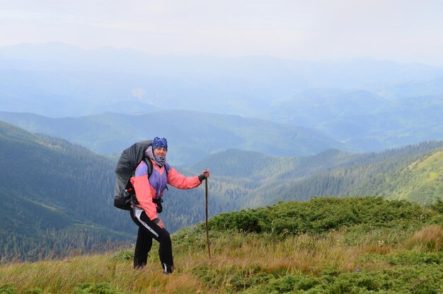 Un giovane turista con un grande zaino e un bastone in alta montagna