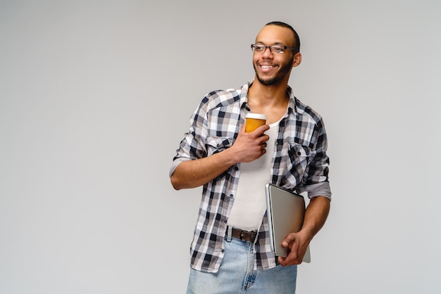 Un giovane uomo afroamericano che tiene pc portatile e tazza di caffè