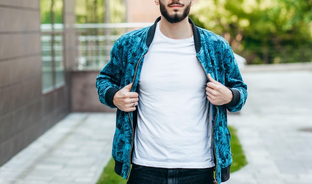 Un giovane uomo alla moda con la barba in una maglietta bianca e occhiali da sole