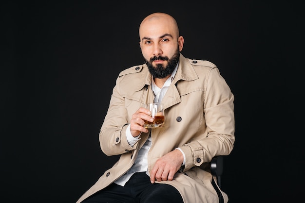 Un giovane uomo alla moda con la barba su uno sfondo nero in studio.