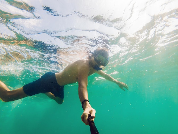 Un giovane uomo caucasico che fa snorkeling sott'acqua selfie thailand