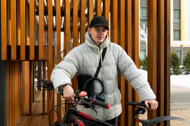 Un giovane uomo caucasico con una giacca grigia e un berretto nero ha noleggiato una bicicletta