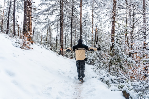 Un giovane uomo che cammina con un maglione di lana bianca nella foresta innevata del parco naturale di Artikutza a oiartzun