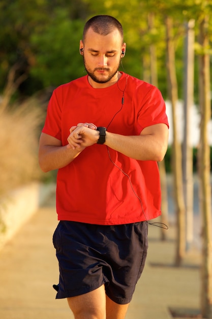 Un giovane uomo che cammina e controlla il tempo sull&#39;orologio