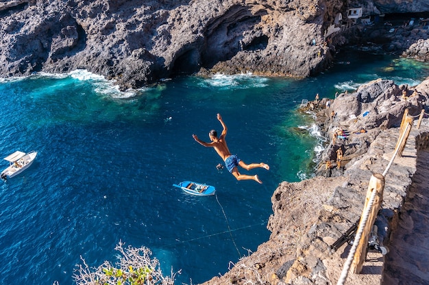 Un giovane uomo che fa un salto molto alto in acqua nella città di Poris de Candelaria, sulla costa nord-occidentale dell'isola di La Palma