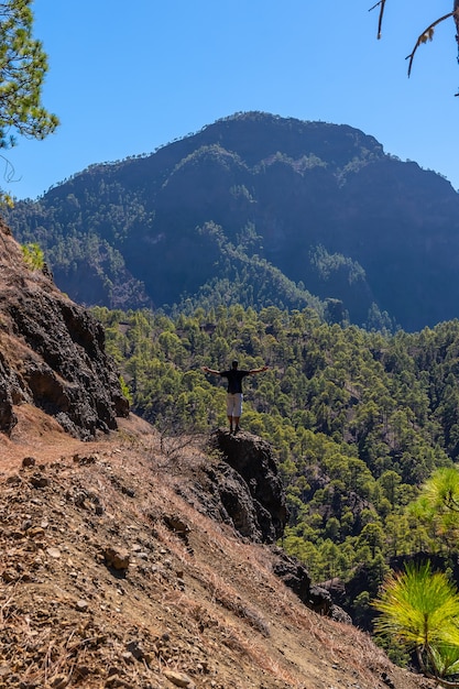 Un giovane uomo che guarda il paesaggio durante il trekking dalla cima di La Cumbrecita accanto alle montagne della Caldera de Taburiente, l'isola di La Palma, Isole Canarie, Spagna