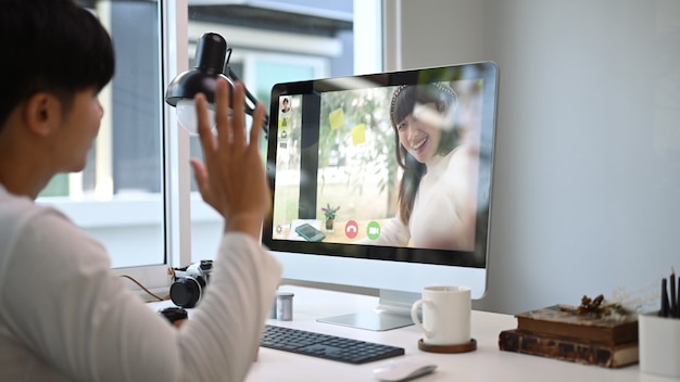 Un giovane uomo che utilizza videochiamata in conferenza sul portatile con la sua ragazza.