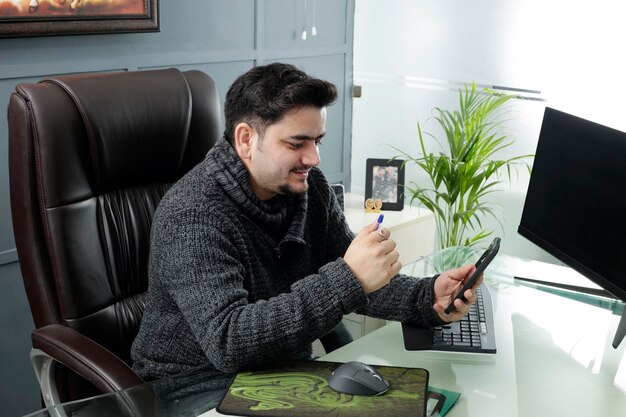 Un giovane uomo d'affari è seduto in ufficio e parla in videochiamata.