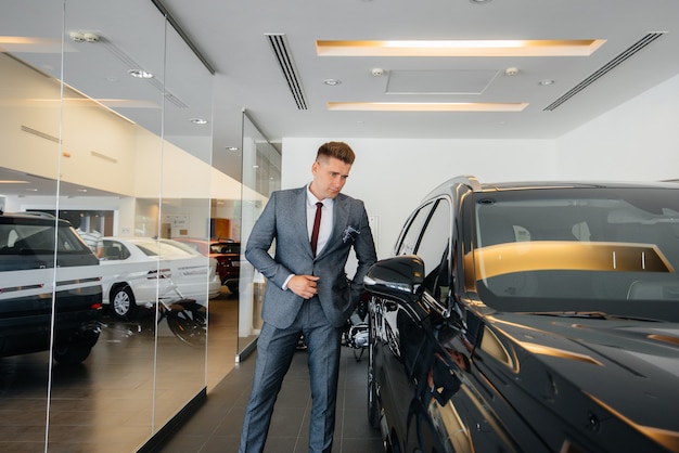 Un giovane uomo d'affari guarda una nuova auto in una concessionaria di automobili