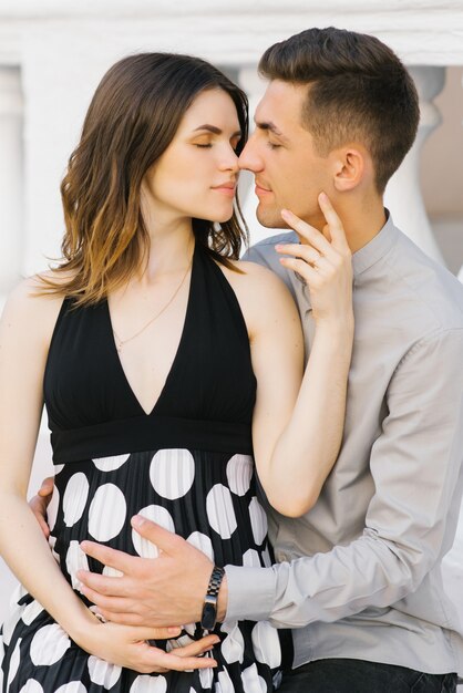 Un giovane uomo di famiglia e una donna in attesa del loro primo figlio, un bacio