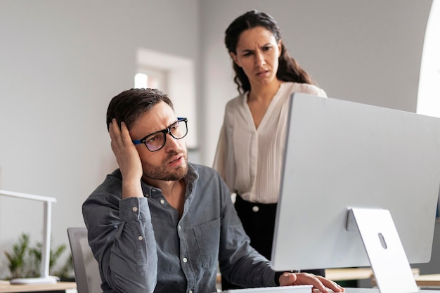 Un giovane uomo europeo triste e disperato e una donna manager che guardano lo schermo del computer trovano un errore