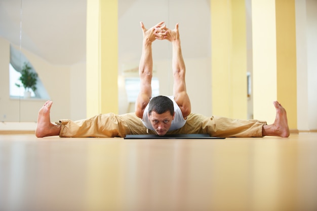 Un giovane uomo forte che fa esercizi di yoga - Samakonasana Posa ad angolo retto in studio di yoga