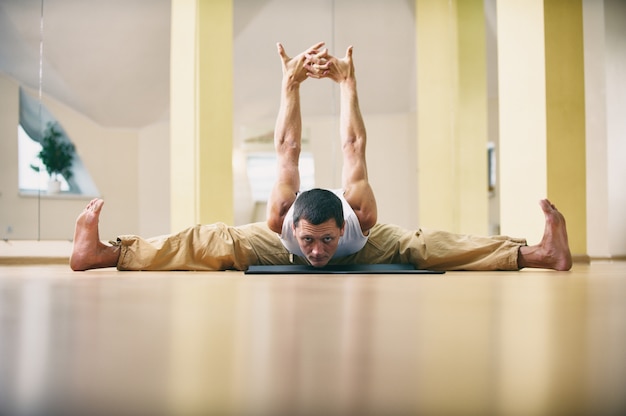 Un giovane uomo forte che fa esercizi di yoga - Samakonasana Posa ad angolo retto in studio di yoga